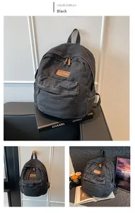 Detail view of a vintage black denim backpack with leather patch and zipper pockets