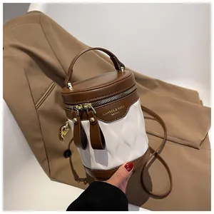 Detail of a color-block bucket bag showing brown leather trim and quilted white texture