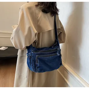 Detail of dark blue denim messenger bag showing retro wash and front zipper pockets
