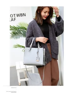 Detail of grey crocodile pattern tote with contrast snake print handles on female model