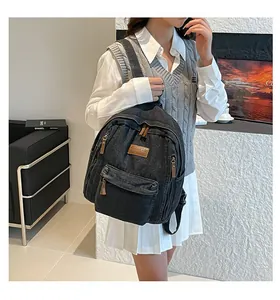 Detail of black denim backpack showing side pocket and leather puller in casual setting