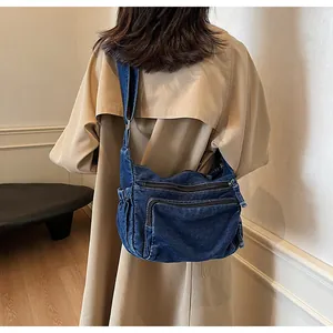 Detail of blue denim messenger bag with multi-zipper pockets and adjustable strap