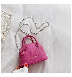 Vista macro della mini borsa a conchiglia rosa con grana litchi e catena argento