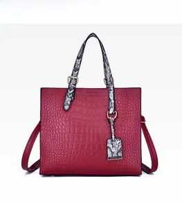 Detailed view of red crocodile-pattern tote bag with contrasting snakeskin handles