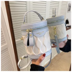 Detail of the wave quilting and gold metal zipper on the light blue contrast bucket bag