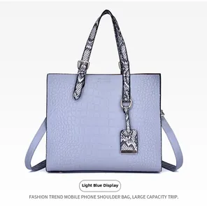 Detail of light blue crocodile embossed leather tote with snake print handles and gold hardware
