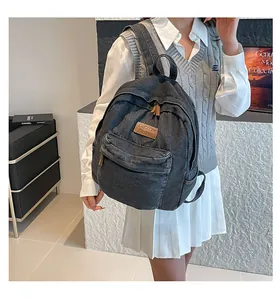 Detail of vintage charcoal denim backpack with brown leather logo and zipper pulls