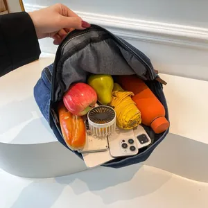 Large capacity blue denim backpack showing interior space with daily travel essentials
