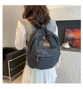 Detail view of the durable denim canvas backpack featuring a decorative leather patch and zipper