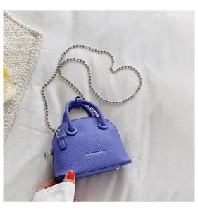 Dettaglio della mini borsa a conchiglia in pelle viola con motivo litchi e catena argento