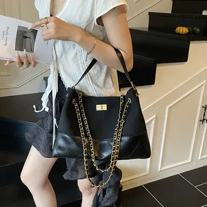 Borsa tote trapuntata nera con catena dorata mostrata in un ambiente studio minimalista