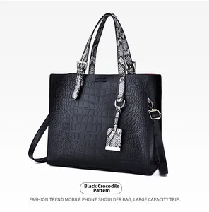 Detailed side view of black tote bag with crocodile texture and snakeskin pattern handles