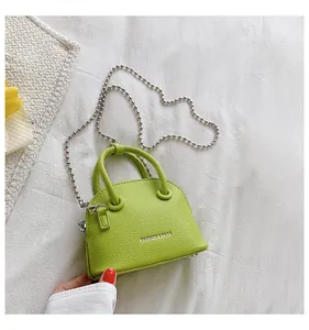 Dettaglio borsa mini verde lime con trama litchi, catena a sfere argentata e testo bianco
