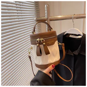 Detail view of cream quilted bucket bag featuring brown leather trim and metallic zippers