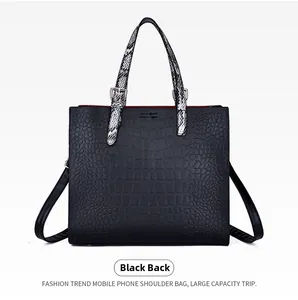 Detail view of large black crocodile embossed tote bag with snakeskin pattern handles