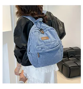 Detail of light blue denim backpack showing texture and front leather logo patch