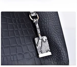 Detail of black crocodile texture tote with gold hardware and snake pattern charm