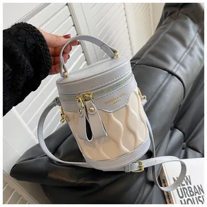 Detailed close-up of blue and beige cylinder bucket bag with wavy quilted texture