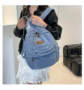 Detailed view of casual blue denim backpack featuring leather logo and front pocket