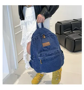 Detail of blue denim backpack with leather logo patch and multi-pocket design features