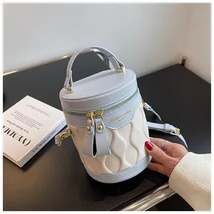 Detailed close-up of light blue wavy quilted bucket bag with gold zipper and handle