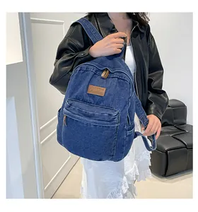 Detail of blue denim backpack showing textured fabric and brown leather logo patch