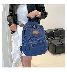 Close-up of a blue denim backpack with brown leather patch on a person's back
