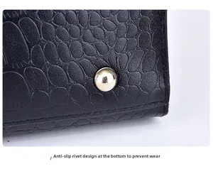Close-up of black crocodile pattern leather tote bottom with protective gold metal studs