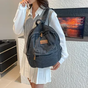 Deep grey vintage denim backpack with leather patch shown on a model in a modern room