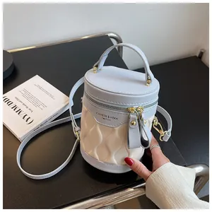 Detail of light blue and cream bucket bag with wavy quilting and gold-tone zippers