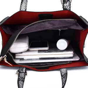 Large black tote bag with red lining and snake skin handles showing spacious interior