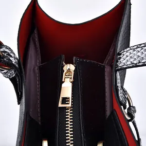 Black leather tote bag with vibrant red interior and premium gold zipper detail