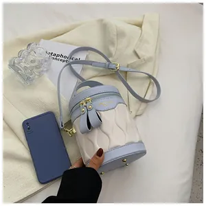 Detail of color-block bucket bag with wave quilting and golden metal bottom studs