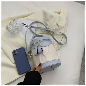 Detail of blue and cream color block bucket bag with wavy quilting and gold hardware