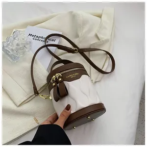 Detail of two-tone bucket bag with wavy texture, gold zippers and metal feet on base