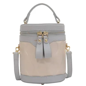 Quilted vanity bag in beige and blue with a round cylinder shape and gold hardware