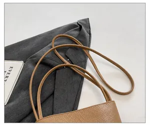 Detailed macro view of the slim brown litchi grain leather strap on a shoulder bag