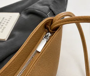 Detail of smooth silver zipper and lychee pattern leather on brown bucket bag