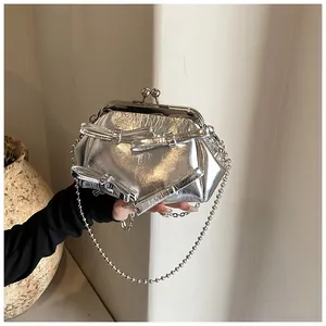 Dettaglio della borsa argento metallizzato con fiocchi e catena a sfere in un set curato