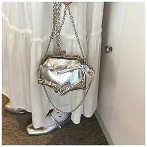 Dettaglio borsa metallizzata argento a pieghe con fiocchi e chiusura a scatto