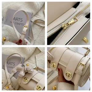 Dettaglio della borsa a cilindro beige con finiture dorate e ciondolo a cane in pelle