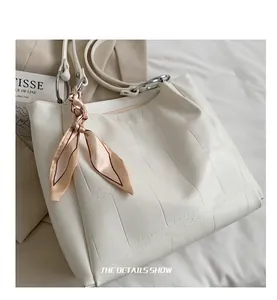 Detail view of crocodile pattern tote bag featuring pleated sides and decorative silk scarf