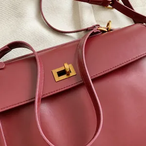 Dettaglio ravvicinato della fibbia in metallo dorato su una borsa in pelle bordeaux
