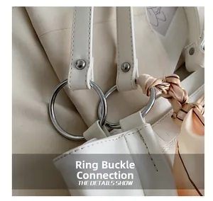 Close-up of white leather handbag featuring silver ring buckle and decorative silk scarf