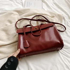 Dettaglio della borsa tote rosso vino con chiusura girevole dorata e texture in pelle