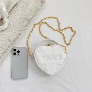 Dettaglio della borsa a tracolla bianca a forma di cuore con catena e smartphone di scala