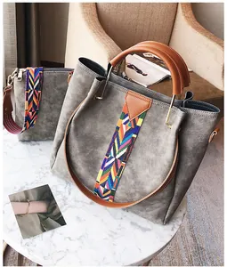 Detail of grey bucket bag with colorful woven shoulder strap on marble table