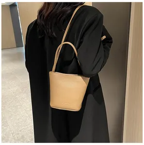 Close-up of litchi grain texture on beige bucket bag styled with a black coat