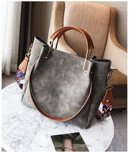 Detail of grey leather tote with ethnic woven strap on a white marble table