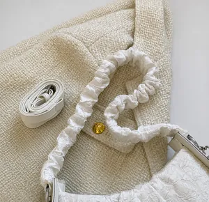 Dettaglio del manico a nuvola plissettato bianco e trama del tessuto di una borsa a tracolla